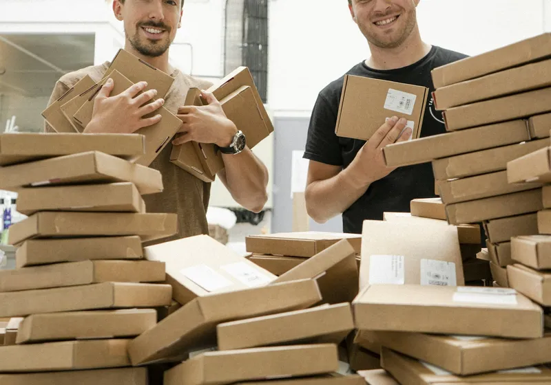 Two people with stacks of packed boxes
